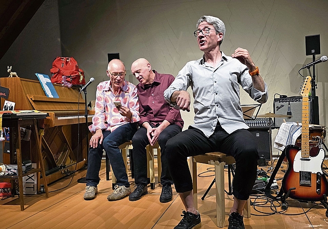 Daniel Buser und Roland Suter schauen gespannt aufs Handy und hören, was Franz Hohler, alias Michael Wernli, ihnen mit seinem imaginären Cello für ein Lied singt.Foto: U. Roth