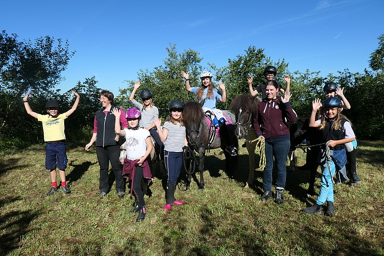 Auf dem Reitplatz freuen sich (v. l.) Ben, Leiterin Sibylle Müller, Anna Sofia, Doreen, Stella, Lynn, Lyam, Co-Leiterin Eileen, Duja, Alisha mit den Ponys und Islandpferden Vanilla, Rökkva, Skjoni und Maja. Foto: U. Handschin