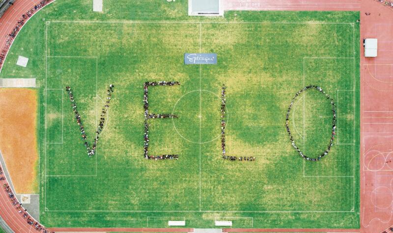 Auf der Wiese bildeten die Schülerinnen und Schüler das grosse Wort «VELO».Foto: zVg